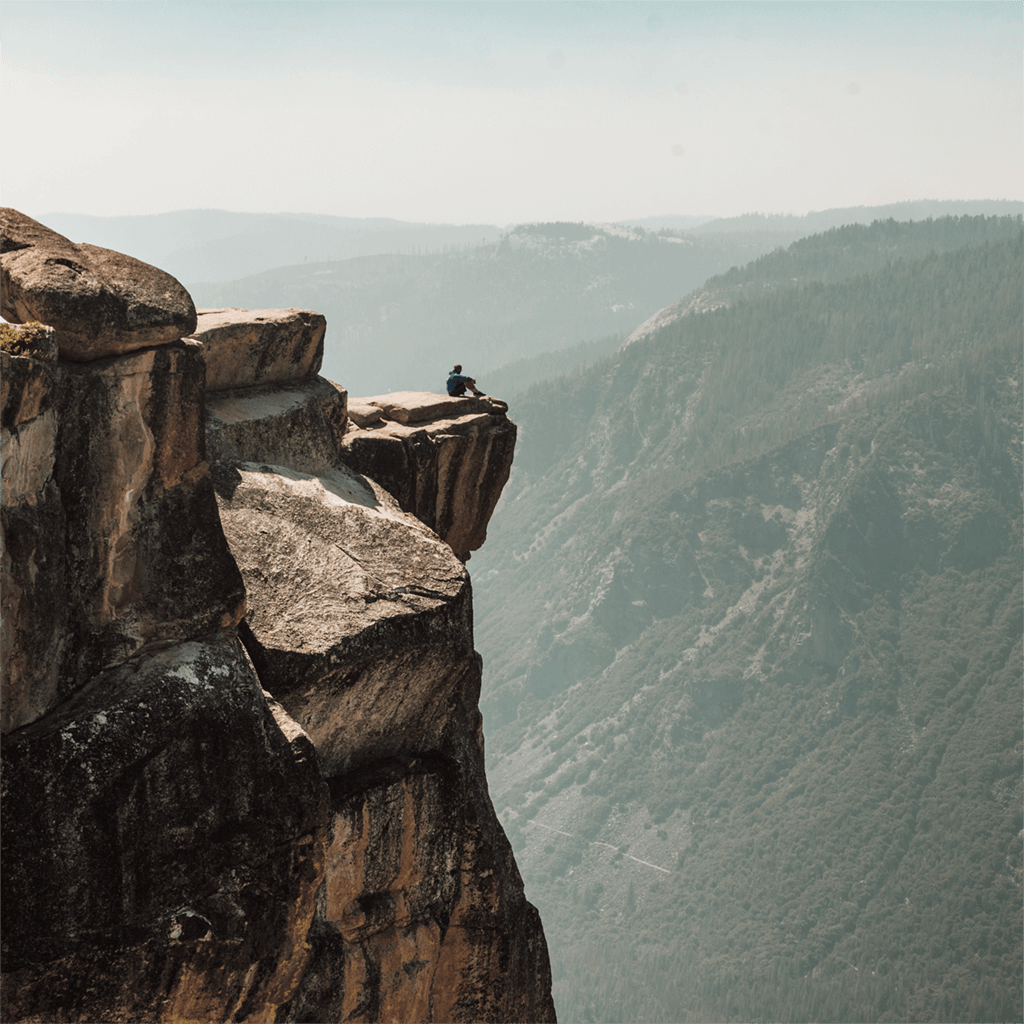 man sitting on edge of cliff