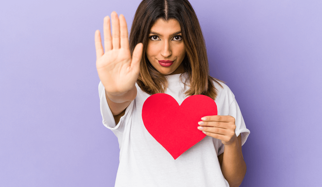 woman holding heart with hand held out in stop gesture